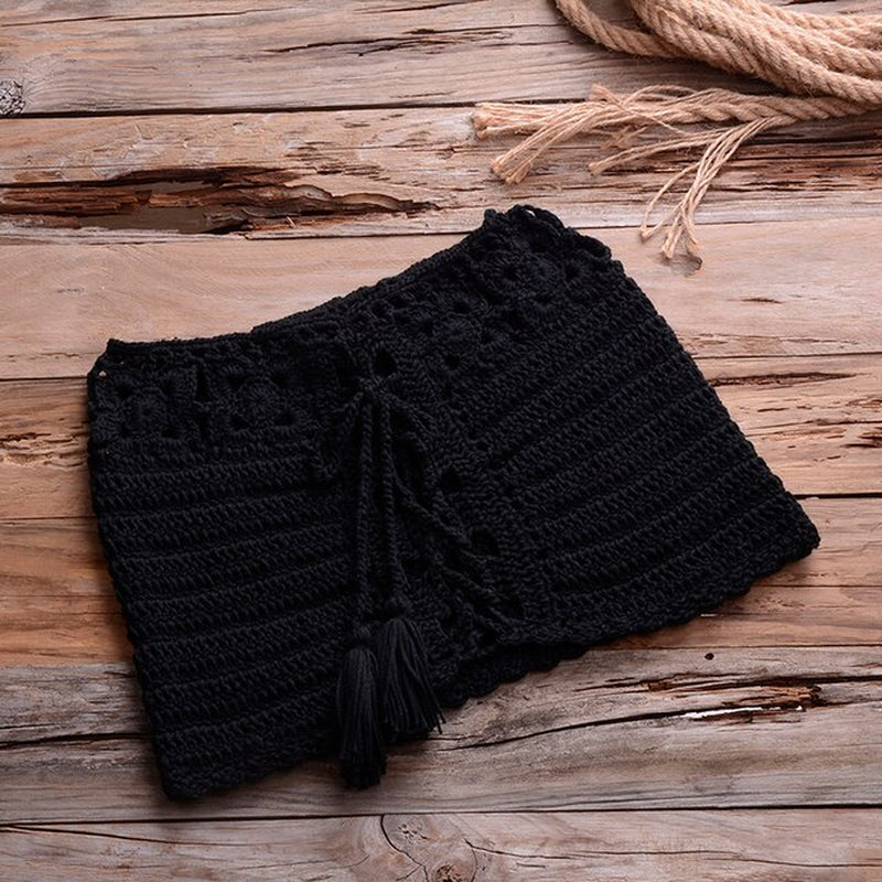 Stylish black crocheted bikini bottoms on rustic wood surface with rope accent