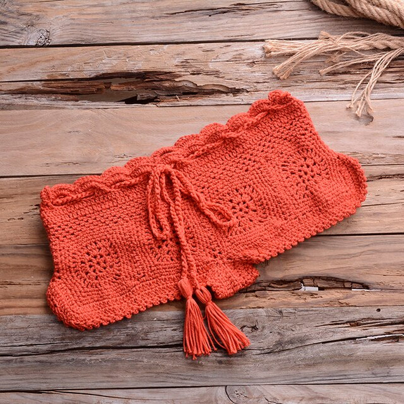 Red crochet bikini set with tassel details on wooden background