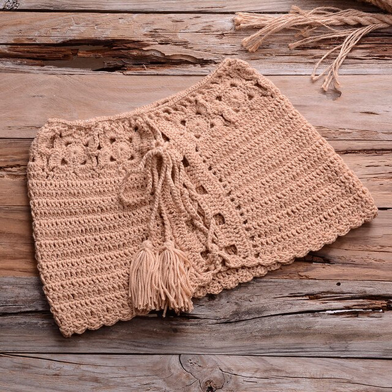 Handcrafted crochet bikini set on rustic wooden background, featuring intricate patterns and tasseled detailing for a stylish summer look.